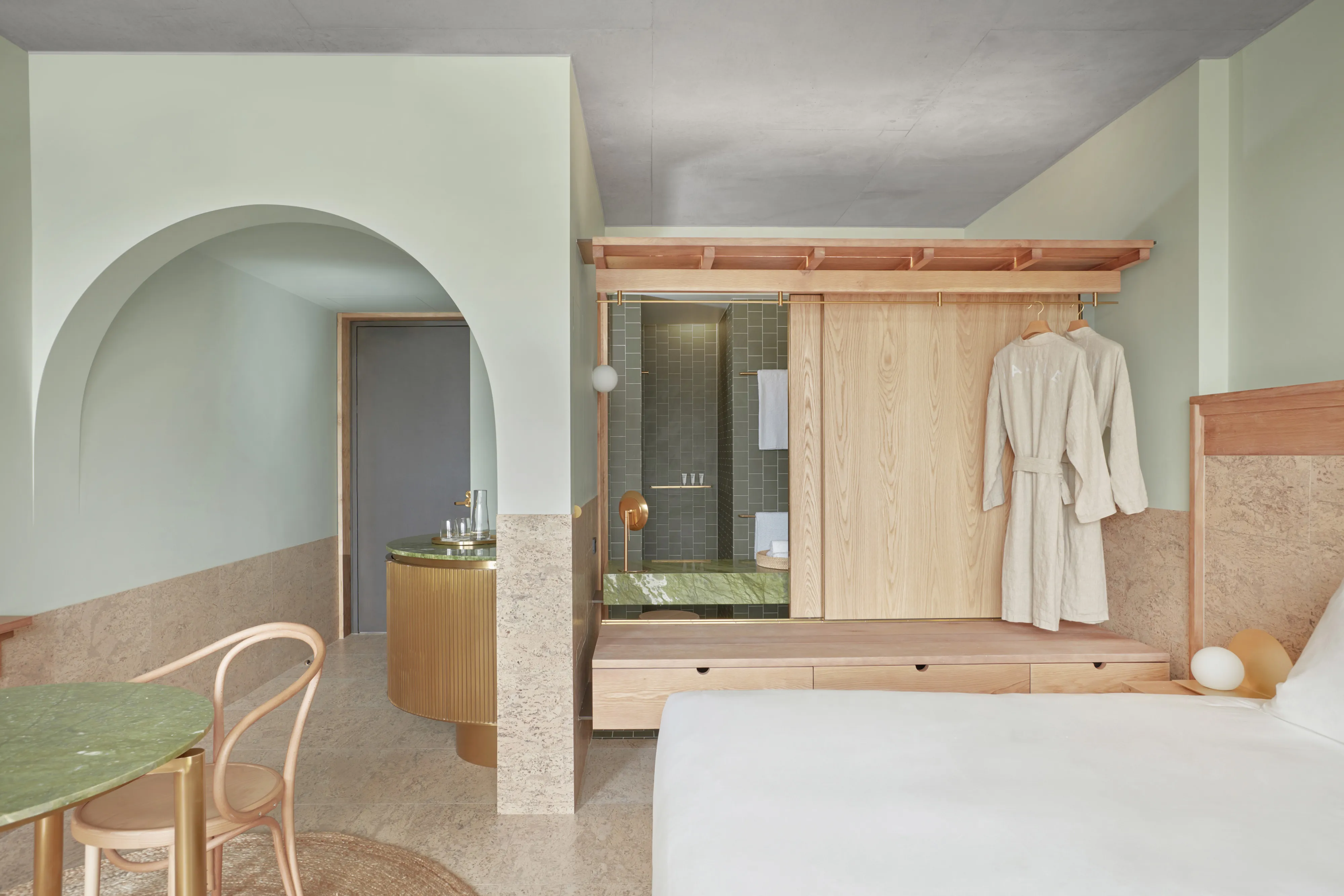 A Calile city-view room with arched joinery, green accent walls, and a wooden wardrobe.