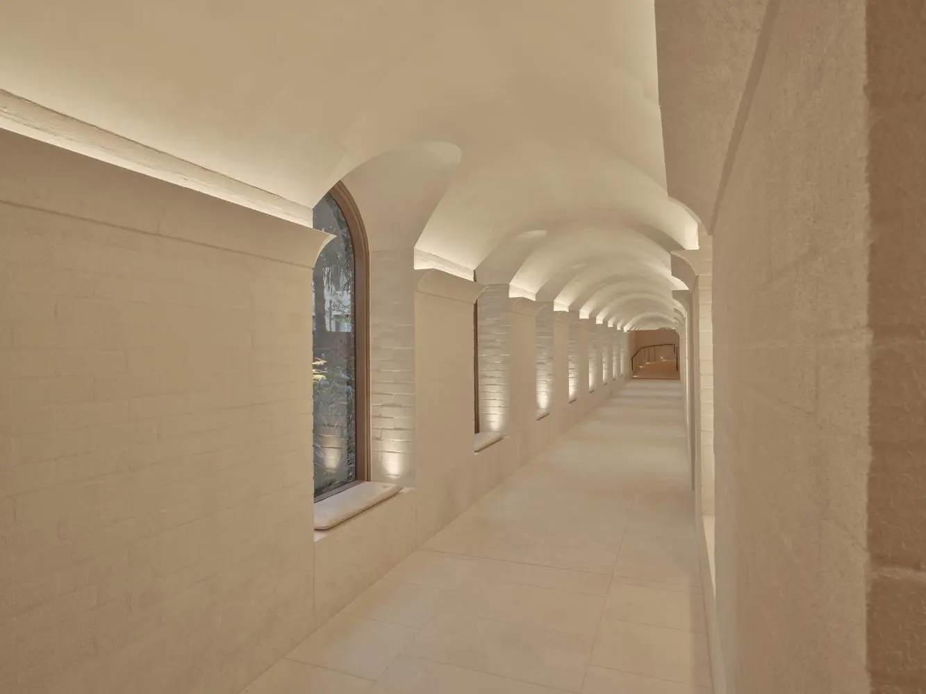 The Eve Hotel arched lobby corridor in cream brick with linear lighting under barrel vaults.