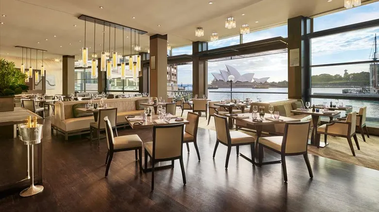 The Dining Room with harbour view through bronze-framed glass.